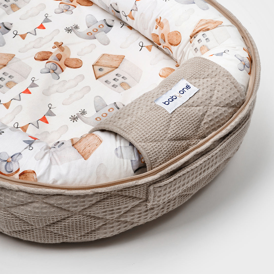 BabyOne portable crib with soft bedding and safety rails, designed for comfortable baby naps and easy mobility.